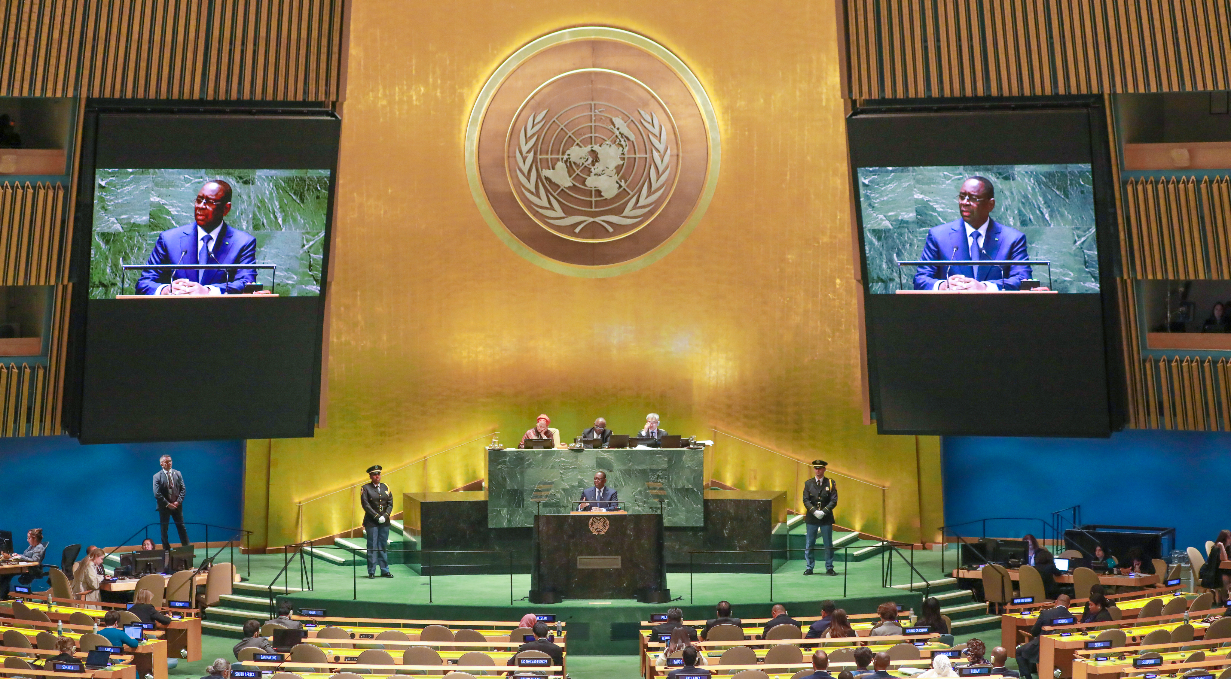 Two women sitting at a modern table talking with a city view behind them.